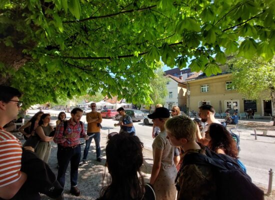 Photo 3: Domen Žalac pointing out post-modern houses along a touristified street next to Gradaščica river. A socialist block is visible behind. (©Thurner, 2023)